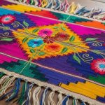 Traditional Mexican textile featuring colorful geometric patterns and embroidered floral motifs on handwoven fabric