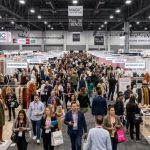 Crowded fashion trade show floor at MAGIC Las Vegas 2026 with exhibitor booths displaying autumn apparel and accessories collections