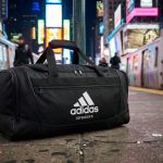 Black adidas Defender 5 duffel bag on a New York platform.