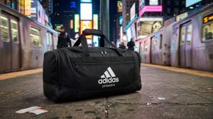 Black adidas Defender 5 duffel bag on a New York platform.