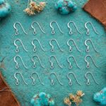 Sterling silver earring hooks displayed on rustic turquoise desert stone.