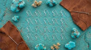 Sterling silver earring hooks displayed on rustic turquoise desert stone.
